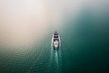 containers ship sailing on green sea aerial view
