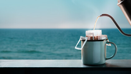 Dripping Coffee by the Sea Side at Morning. Making Hot Drink by Pouring Hot Water from kettle into...
