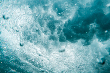 Fototapeta na wymiar Underwater View of Wave Crashing to Shore Spraying Drops of Water Across the Sea