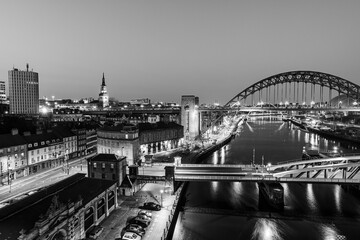 Obraz premium Newcastle upon Tyne UK: 30th March 2021: Newcastle Gateshead Quayside at night, with of Tyne Bridge and city skyline, long exposure in monochrome
