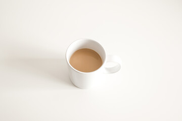 white ceramic cup of hot coffee with milk on a white wood table and refreshing look of the drink, with a clean background.