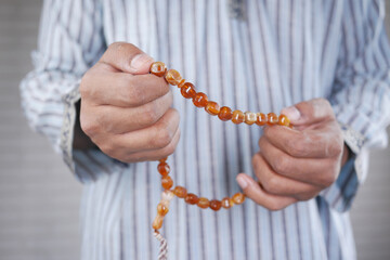 Close up of muslim man hand with rosary praying on ramadan 