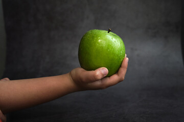the girl holds a green apple in her hand