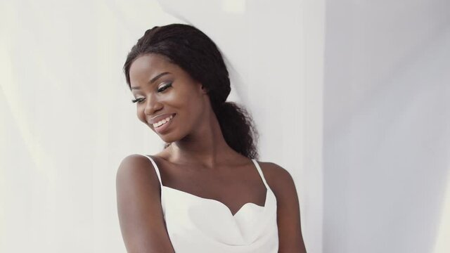 Attractive black woman in white top smiling at camera, beauty of diversity