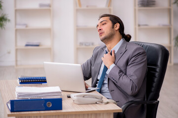 Fototapeta premium Young male employee unhappy with excessive work in the office
