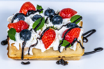 Waffles with whipped cream and fresh fruit. The food in the restaurant. Food styling and restaurant meal serving.