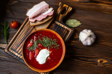 Ukrainian borscht in a vintage ceramic plate on a cutting Board with a set of vegetables for cooking on a dark wooden background. Background.