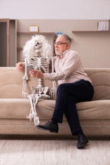 Old man sitting on the sofa with the female skeleton