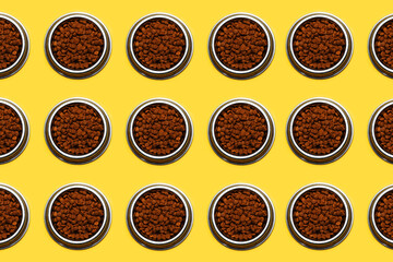 Pattern of steel bowls with dry food for cats on background of yellow color.