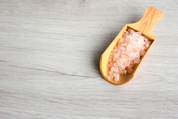 Colorful rock salt in wooden spoon on a white background