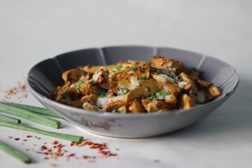 Cheesy potato wedges made by baking air fried potato wedges after sprinkling it with shredded mozzarella, chilli flakes and chopped green onions.