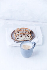 Cappuccino and sweet bun on bright wooden background. Copy space.