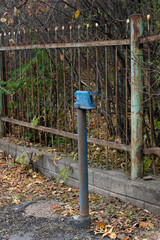 An old water column with a blue tap on the street.