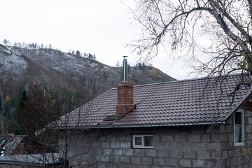 The roof of a residential building with a metal pipe.