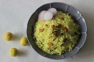 Lemon rice made by seasoning cooked rice with spices, leaves, turmeric and lime juice.