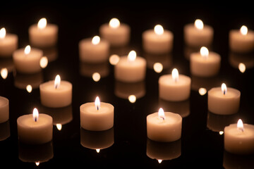 Fototapeta na wymiar some tee candles on a black acrylic underground, background blurred