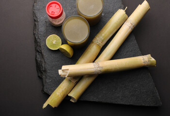 Sugarcane juice in glass with piece of sugarcane, lemon and black salt 