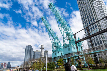 Brooklyn, NY - USA - April 17, 2021:The Gantry Cranes at the north end of Domino Park. A public park in the Williamsburg neighborhood of Brooklyn, the former site of the historic Domino Sugar Refinery - obrazy, fototapety, plakaty