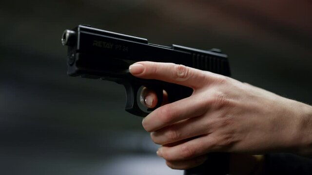 Policewoman shooting with loaded gun. Cop holding finger on trigger of pistol