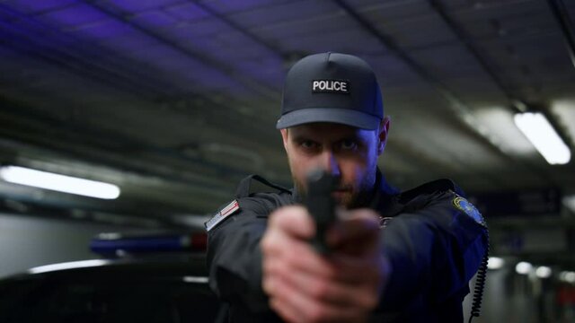 Policeman shooting with gun. Male cop aiming pistol at camera