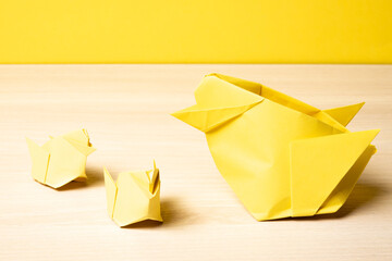 Yellow origami hen and chicks on a wooden table with copyspace