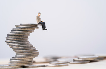 Old man miniature figure sitting on coins stacking with copy space , Saving Financial plan of aging...