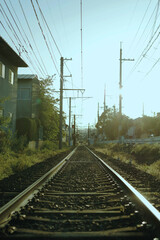 Fototapeta na wymiar Vertical photo of railway tracks in the morning. Sunlight hitting on the rail tracks. Electrical wire and cables. Local tram train tracks in Kyoto, Japan.