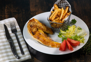 Roasted dinner on white plate containing chicken and potato, homemade fries, High quality photo