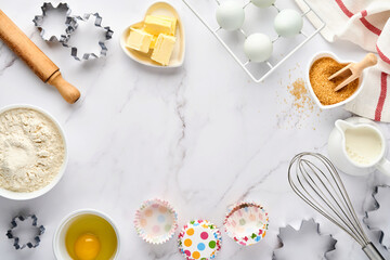 Baking background with flour, eggs, kitchen tools, utensils and cookie molds on white marble table. Top view. Flat lay style. Mock up.