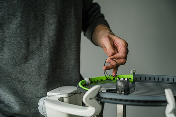 Close-up of tennis racket on electronic stringing machine. Process of replacement synthetic gut string before game. Stringer makes knot.