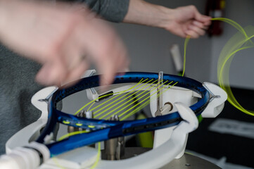 Close-up of tennis racket on electronic stringing machine. Process of replacement synthetic gut...