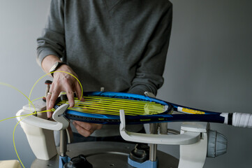 Close-up of tennis racket on electronic stringing machine. Process of replacement synthetic gut...