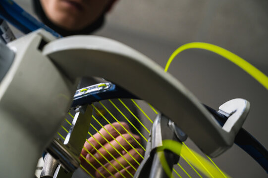 Close-up of tennis racket on electronic stringing machine. Process of replacement synthetic gut string before game. Bottom view.