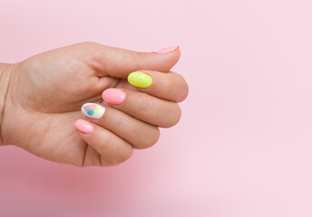 Female hand with summer manicure with ice cream on pink background
