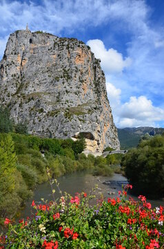 Castellane in Alpes-de-Haute-Provence along the route Napoleon, France, church on top of a rock, blue sky with clouds background, stone bridge over Verdon river