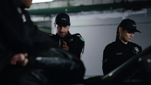 Police officers arresting criminal at parking. Male cop aiming man with gun