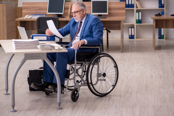 Old businessman employee in wheel-chair working in the office