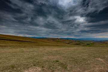 Obraz premium Gathering dramatic stormclouds over the green valley at early spring in Transylvania.