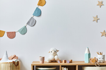 Stylish scandinavian newborn baby room with toys, plush animal, photo camera, doll and child accessories. Cozy decoration and hanging cotton balls on the white wall. Copy space.