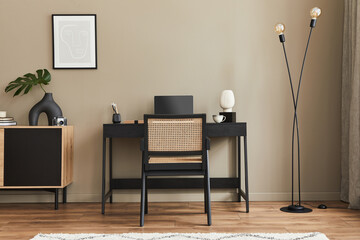 Modern interior design of home office space with stylish chair, desk, commode, black mock up poster...