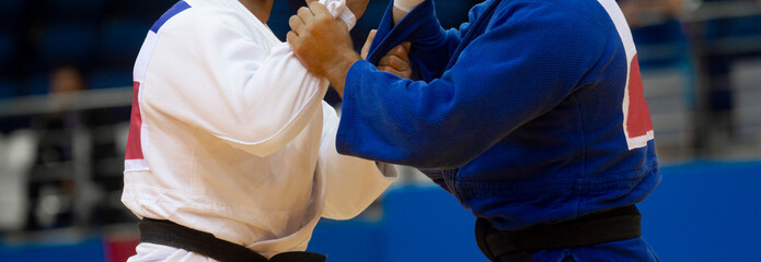 Two judo fighters in white and blue uniform. Professional sport concept