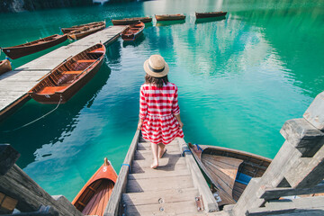 Fototapeta na wymiar young gentle woman in red checkered dress barefoot walking by wooden stairs of boat station leads to lake