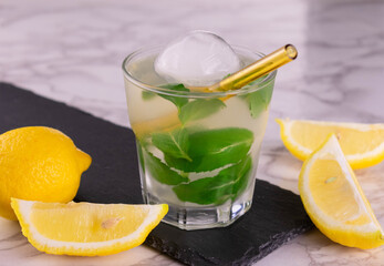 A glass of refreshing mojito with lemon and mint.
Close-up.