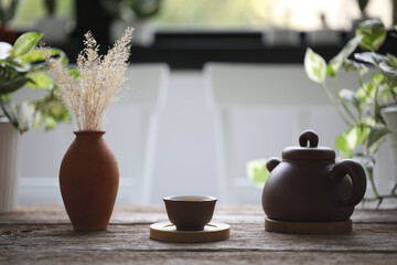 teapot and tea cup with pot of dry grasses on wooden table