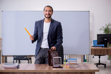 Young male teacher physicist in the classroom