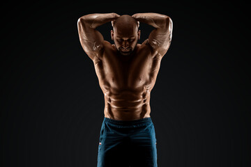 Tattooed male bodybuilder posing over black background. Fitness workout concept, muscle groups,...