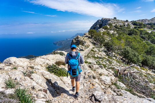 Schönes Mallorca: Wanderung einer Gruppe im Naturpark über Valldemossa auf dem historischen Reitweg des Erzherzogs Salvator auf den Caragoli - Mann genießt den Ausblick auf dem Grat
