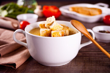 Cheese or onion cream soup with toasts bread in a white bowl