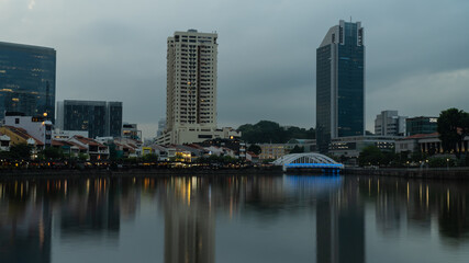 A scene at Boat Quay, Singapore, during sunset with long exposure and reflection of the skyline on the Singapore River