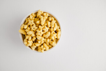 Honey stars breakfast cereal in white bowl. Healthy whole grain taste. Top view. Copy space. Food...